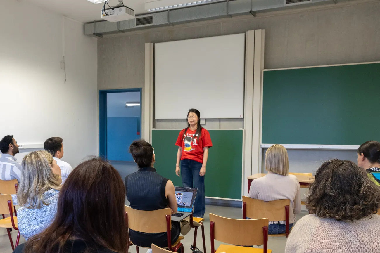 Ying delivering a keynote at Clusity's Summer Gathering, the audience seen from behind
