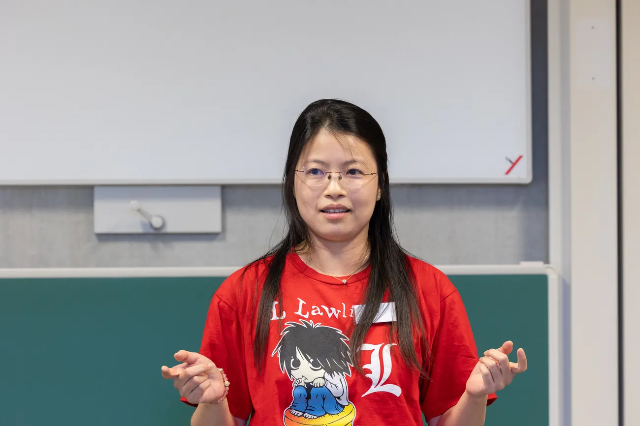 Ying speaking with both hands open, mid-explanation